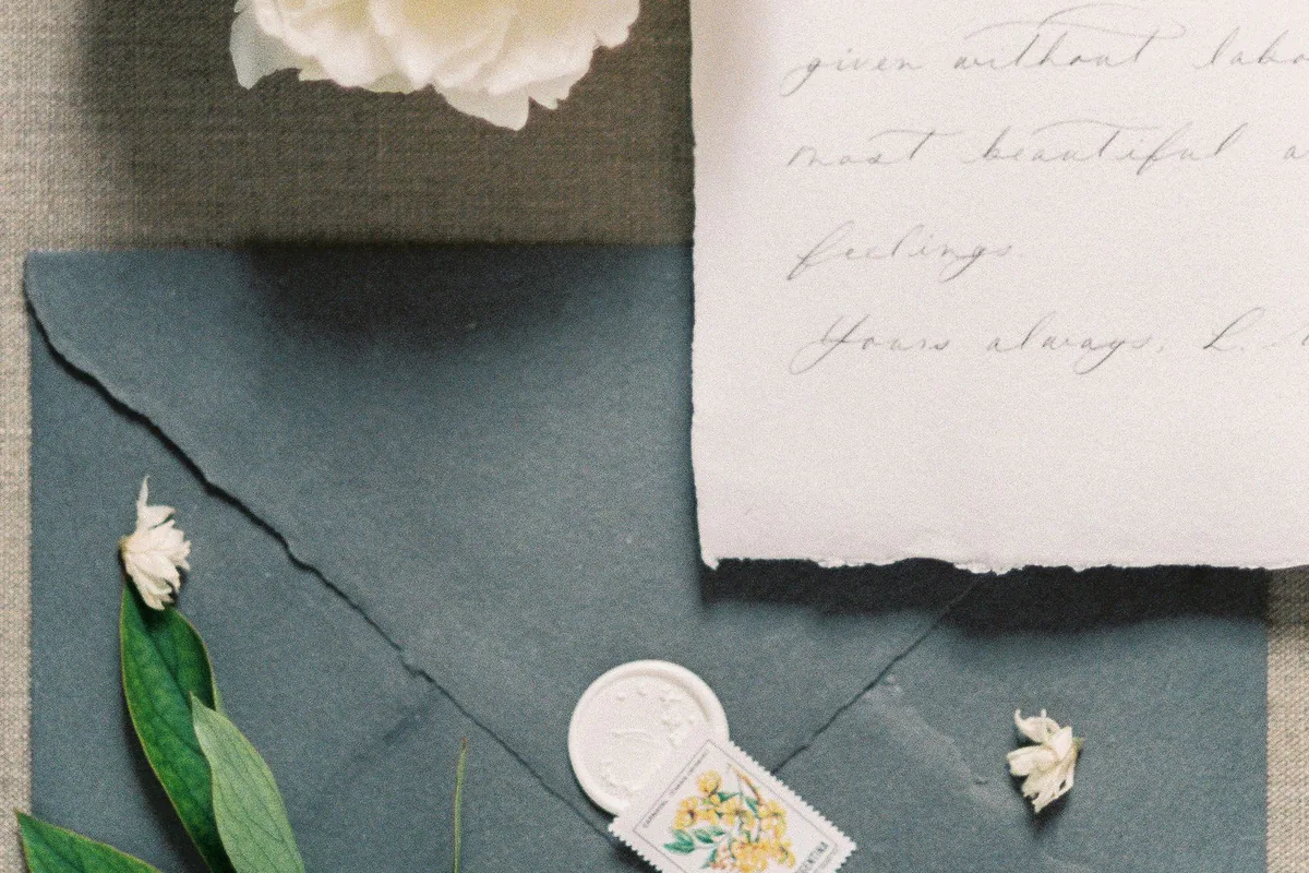 Dunkler Vintage-Umschlag mit heller Blüte, Grün und kleinen Accessoires