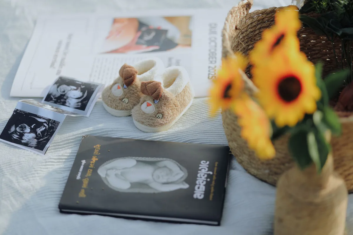 Ultraschallbilder, Babyschuhe und Sonnenblumen auf hellem Stoff