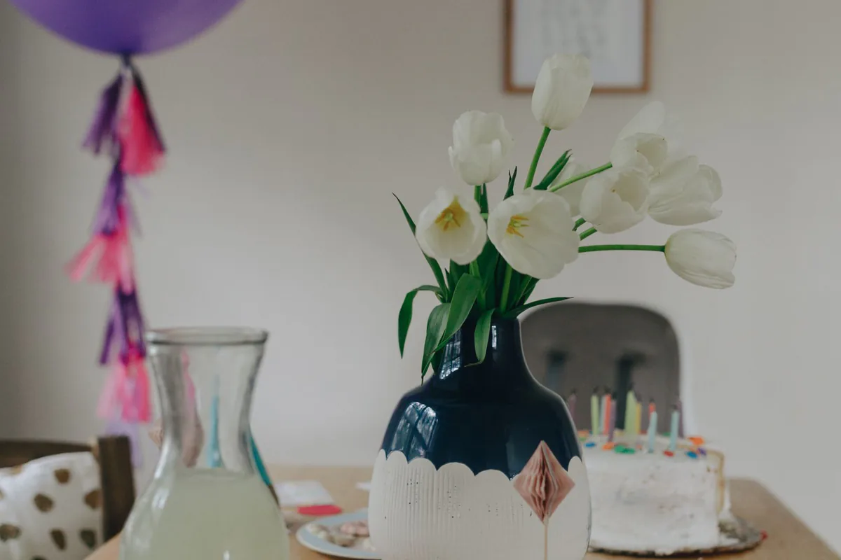 Bunter Geburtstagstisch mit Luftballons, Partyhüten und Geschirr