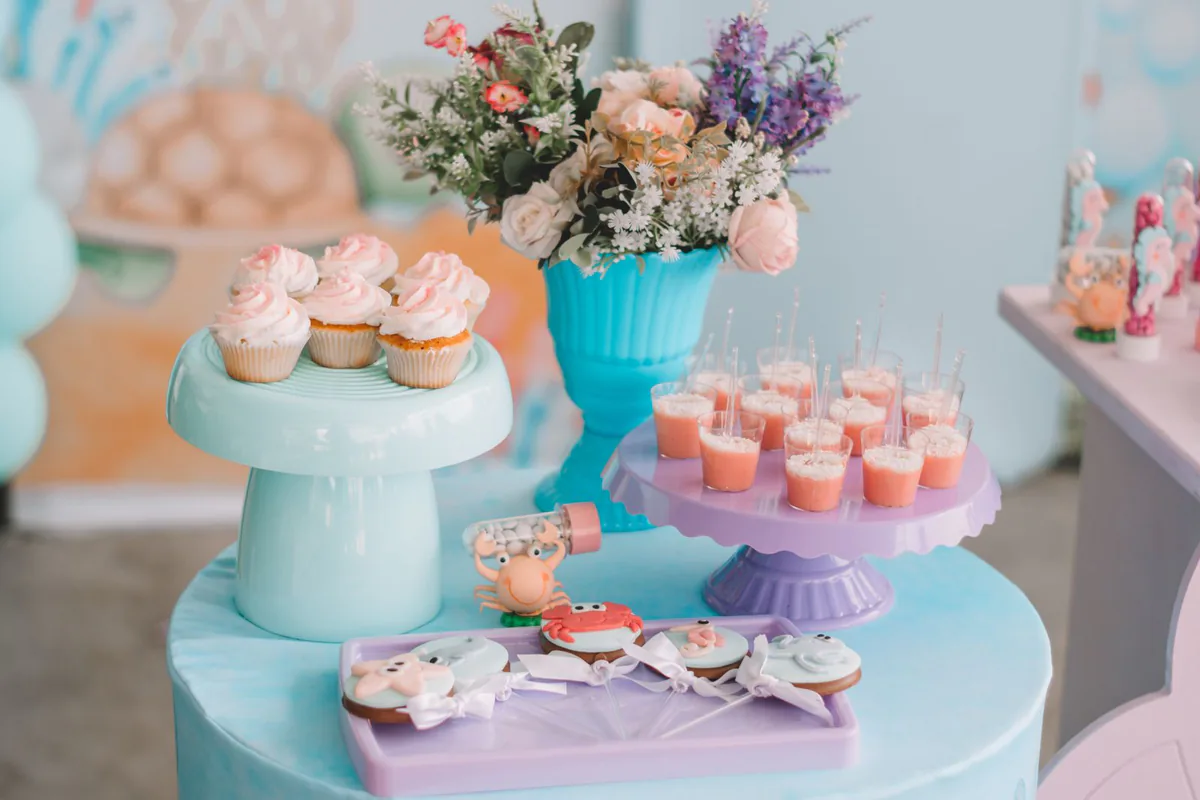 Festlich gedeckte Tafel mit pastellfarbenen Cupcakes, Blumen und kleinen Desserts